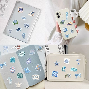 Détail d'autocollants côtiers bleus sur tablette, coque de téléphone et journal DIY