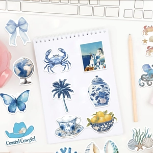 Gros plan d'autocollants bleus de style côtier sur un carnet avec des accessoires