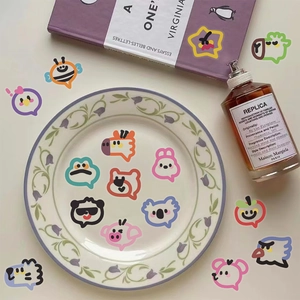 Detailed view of waterproof PET cartoon animal stickers arranged on a floral porcelain plate