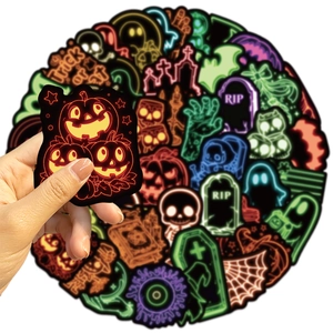 Detail showing hands holding a neon Halloween pumpkin sticker with skull and ghost patterns