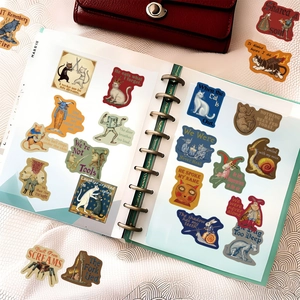 Artistic surrealism stickers with dark fairy tale themes displayed in a spiral notebook