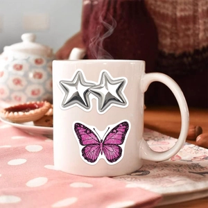 White ceramic mug with silver stars and pink glitter butterfly on a polka dot tablecloth