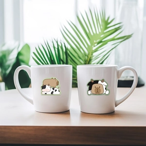Gros plan de deux tasses en céramique blanche avec d'adorables dessins de Capybara