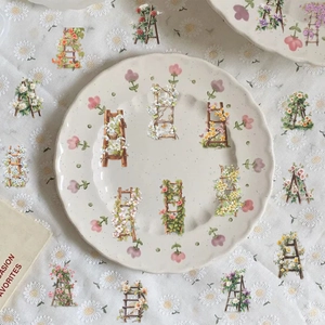 Dettaglio di 50 adesivi floreali vintage in PET con scale e fiori su un panno bianco