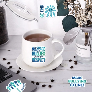 Detail of waterproof anti-bullying stickers on laptop and mug with positive quotes