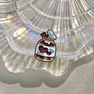 Cute enamel brooch shaped like a love pill bottle with red hearts and metal finish