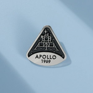 Macro shot of Apollo 1969 moon landing pin with silver texture and enamel finish