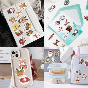Lifestyle view showing Christmas stickers on a tablet, envelope, phone case, and bag