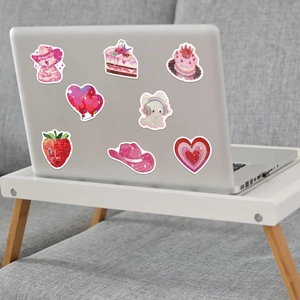 Close-up of cute pink glitter stickers on a laptop featuring cat and cake motifs