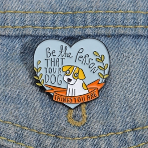 Heart-shaped enamel dog brooch with motivational quote pinned on blue denim jacket