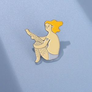 Dettaglio macro di una spilla smaltata artistica con il disegno di una donna bionda
