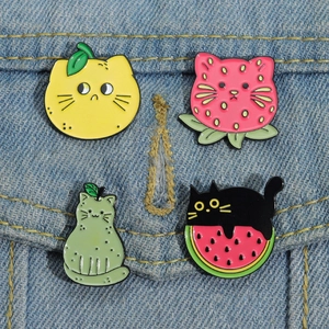 Gros plan de quatre pins chat fruits en émail sur une poche de veste en jean