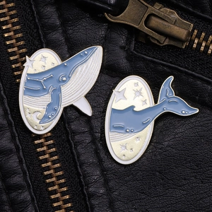 Détail de l'ensemble de deux pin's émaillés baleine étoilée sur fond en cuir noir élégant