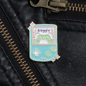 Detailed view of mint green cartoon frog game console enamel pin on black leather jacket