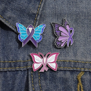 Gros plan détaillé de trois pin's papillons émaillés colorés sur tissu denim bleu