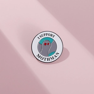 Macro shot of circular enamel pin featuring Mothman with red eyes and I SUPPORT MOTHMAN text
