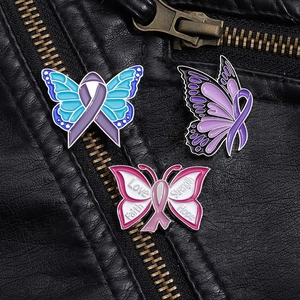 Détail de trois épingles papillon en émail coloré avec mots motivants sur veste en cuir