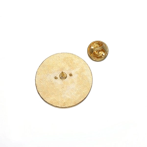 Detailed back view of round gold brooch with honeycomb texture and butterfly clasp