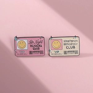 Detail of pink and beige enamel pins featuring VIP member card designs on pink backdrop