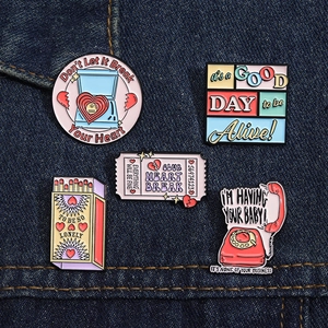 Vue détaillée d'épingles en émail colorées aux motifs rétro sur du tissu en denim