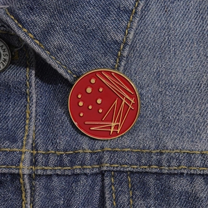 Close-up of a red circle enamel biology badge pinned on a blue denim jacket collar