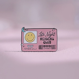 Macro shot of pink enamel badge with Late Night Readers Club text and yellow smiley face