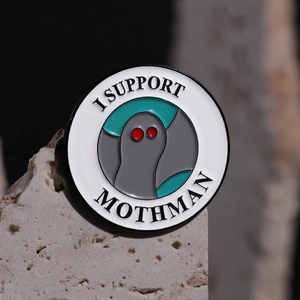 Enamel Mothman pin badge with red eyes and I Support Mothman text on grey rock