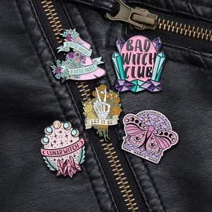 Detailed macro view of five enamel pins featuring witch, skull, and lunar motifs on leather