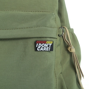 Macro della spilla smaltata I Don't Care Breaking News su tessuto di tela verde