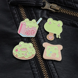 Detalle de cuatro pines esmaltados de postres de rana sobre una chaqueta de cuero