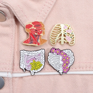 Detailed close-up of four anatomical enamel pins featuring hearts and ribs on pink denim