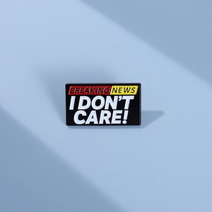Vista macro della spilla rettangolare in smalto con slogan Breaking News I Don't Care