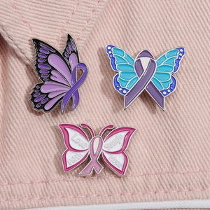 Détail de trois épingles papillon en émail avec mots inspirants sur denim rose