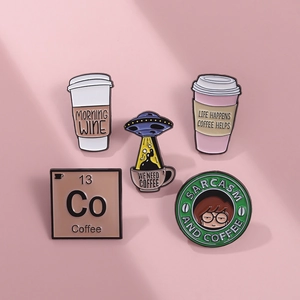 Makro-Detail von fünf Cartoon-Kaffee-Emaille-Pins auf einem zartrosa Hintergrund