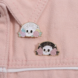 Detail von Emaille-Pins mit Totenkopf und Blumen auf dem Denim-Kragen im Punk-Stil