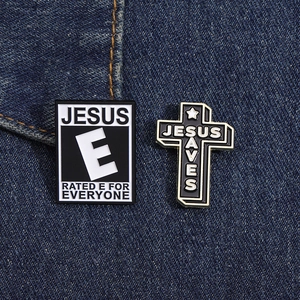 Macro shot of Jesus Saves cross and Jesus E enamel pins on dark blue denim fabric