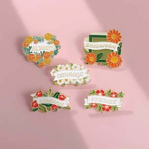 Detailed view of enamel floral brooches with Always, Courage, and Kindness motifs