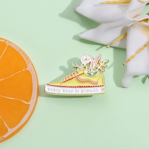 Creative yellow sneaker enamel brooch with white flowers and Every Step Is Growth slogan