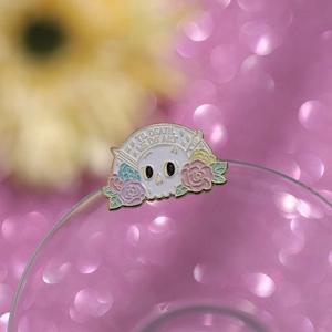 Macro detail of enamel skull pin with colorful flowers and Til Death We Do Art slogan