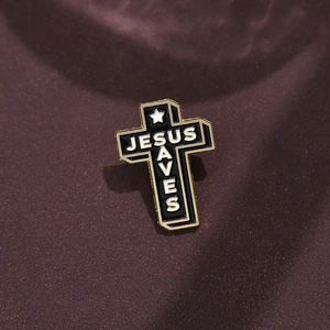 Macro view of Jesus Saves black enamel cross brooch with gold metal plating