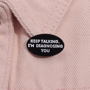 Vue macro d'un badge en émail noir avec un slogan humoristique sur denim rose