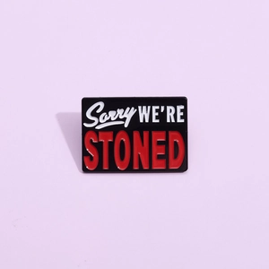 Creative enamel pin with Sorry WE'RE STONED slogan in black red and white design