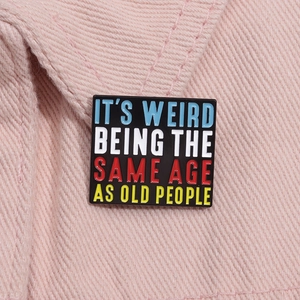 Detail of square enamel pin with quote on pink denim fabric showing secure attachment