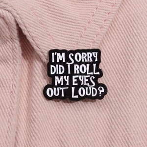 Macro shot of black enamel brooch featuring white text on pink denim fabric lapel