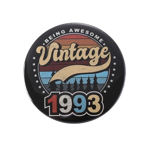 Macro detail of round tinplate badge with vintage 1993 sunset design and forest silhouette