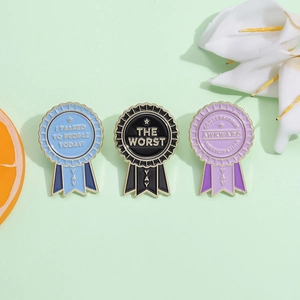 Cartoon award ribbon enamel pins in blue, black, and purple with ironic motivational phrases
