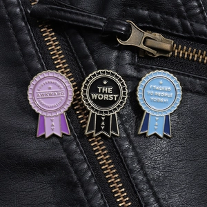 Detailed view of three metal enamel medal pins on a black leather jacket with funny slogans