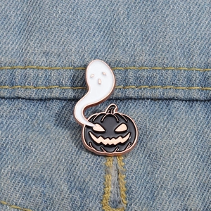 Gros plan du pin's émaillé citrouille et fantôme d'Halloween sur une veste en jean