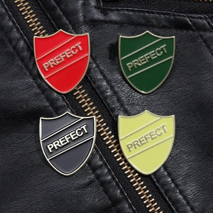 Close-up of shield-shaped enamel pins with Prefect engraving on a black leather jacket