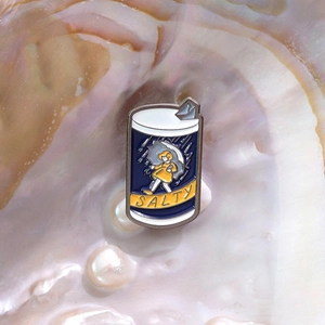 Detail of salty jar enamel pin featuring a girl in yellow raincoat inside a pearl shell